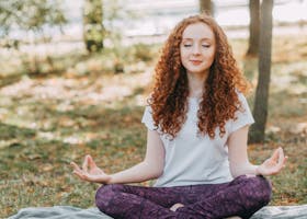 Woman meditating in a serene park during springtime, fostering relaxation and mental wellness.