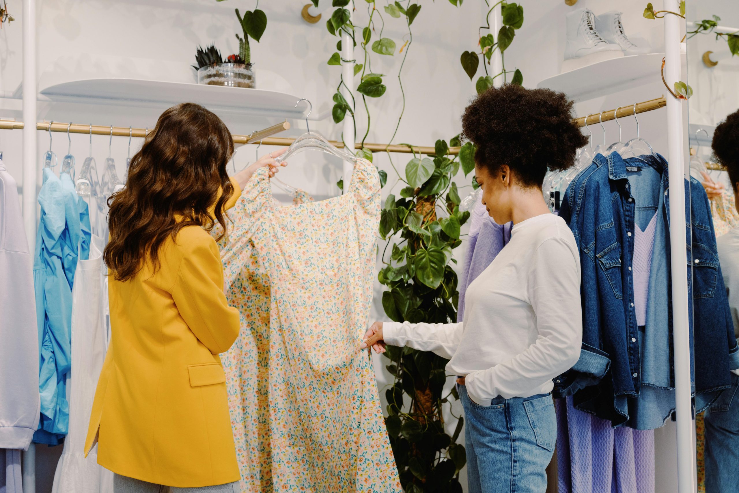 Two women shopping for stylish clothing in a trendy boutique, focused on a floral summer dress.